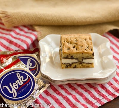 A peppermint stuffed chocolate chip cookie bar on a stack of plates with a couple york peppermint patties