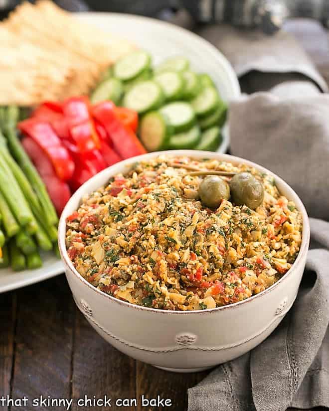 Bowl of Red Pepper Artichoke Tapenade with a platter of fresh vegetables.