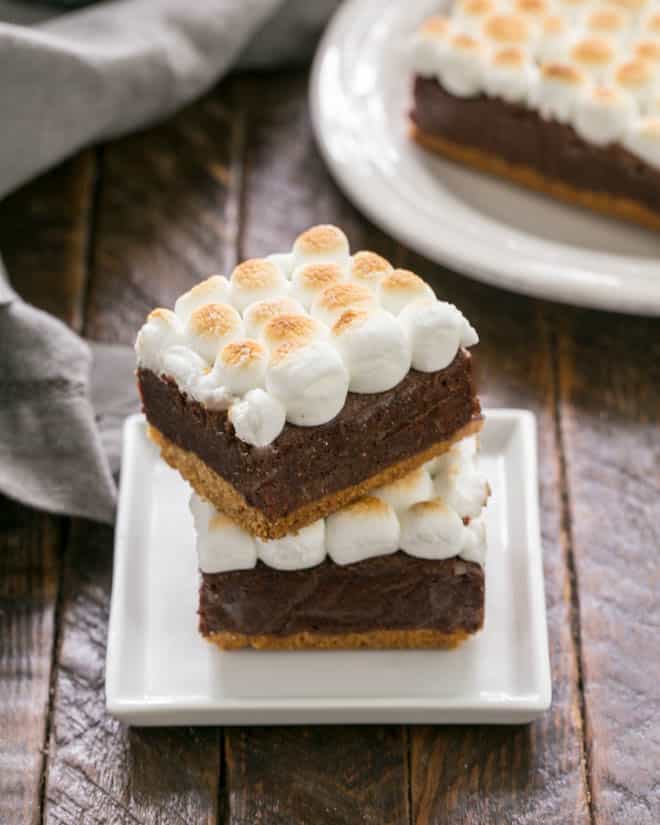 S'mores Brownies with a graham cracker crust stacked on a small square white plate.