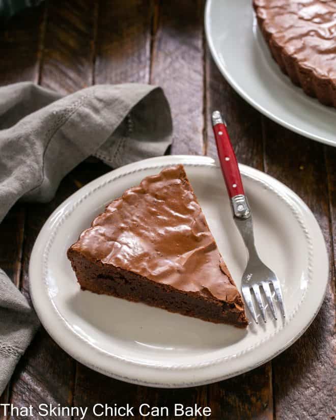 Ungarnished slice of brownie pie on a white dessert plate with a red handled fork.