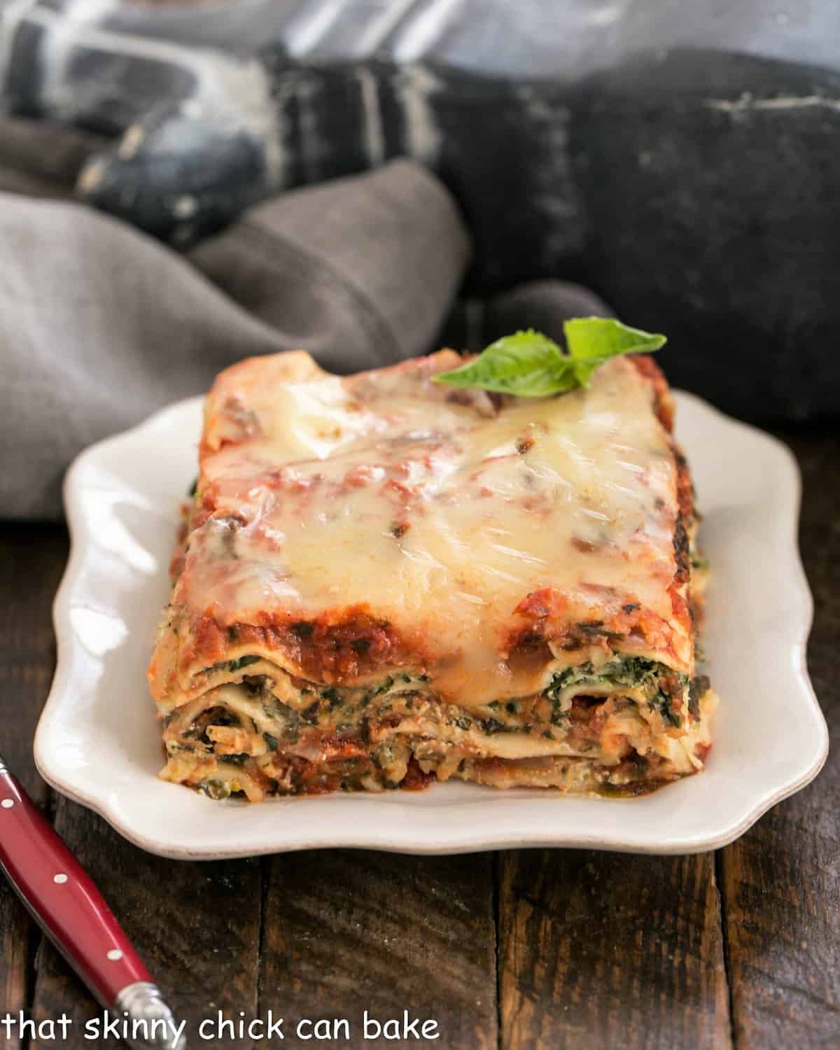Slice of spinach lasagna on a square white plate.