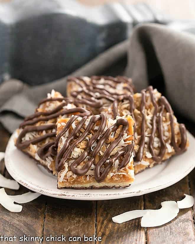 Homemade samoa bars on a round plate with shreds of coconut.