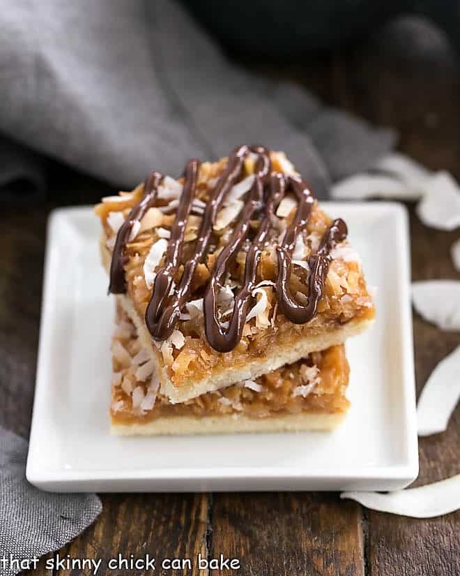 Homemade samoa bars stacked on a white plate.