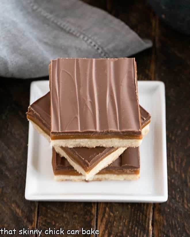 Overhead view of 3 twix bars stacked on a small square white plate