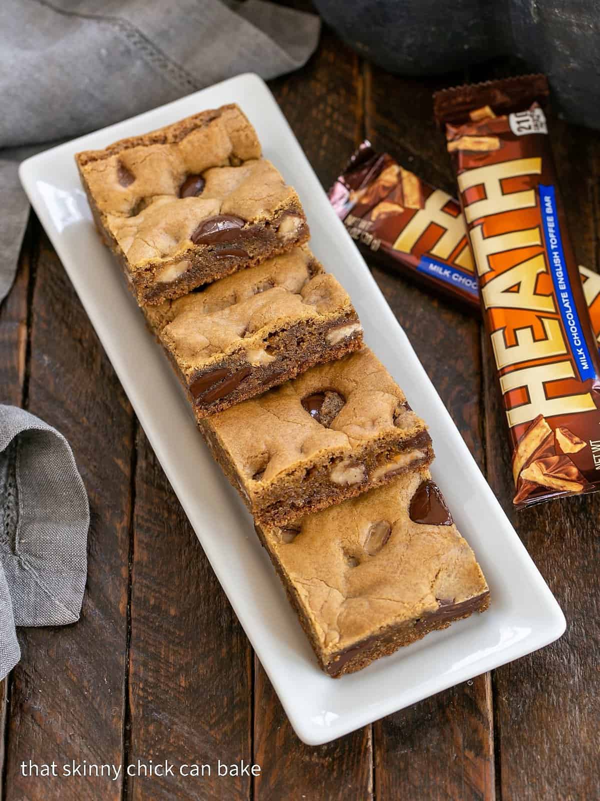 Overhead view of Chocolate Chunk Blondies wtih toffee chunks on a white ceramic tray.