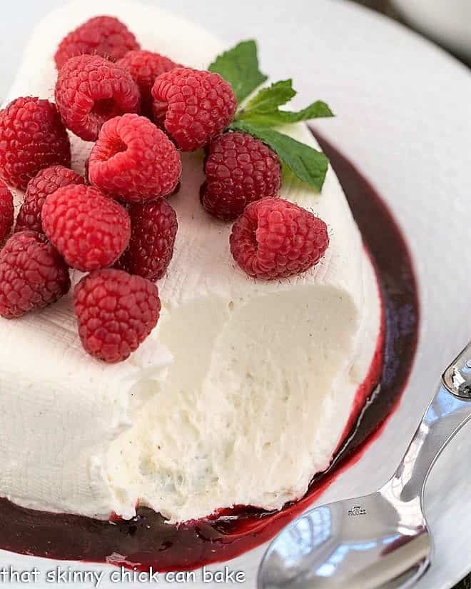 No-Bake cheesecake recipe topped with fresh raspberries with a scoop removed.