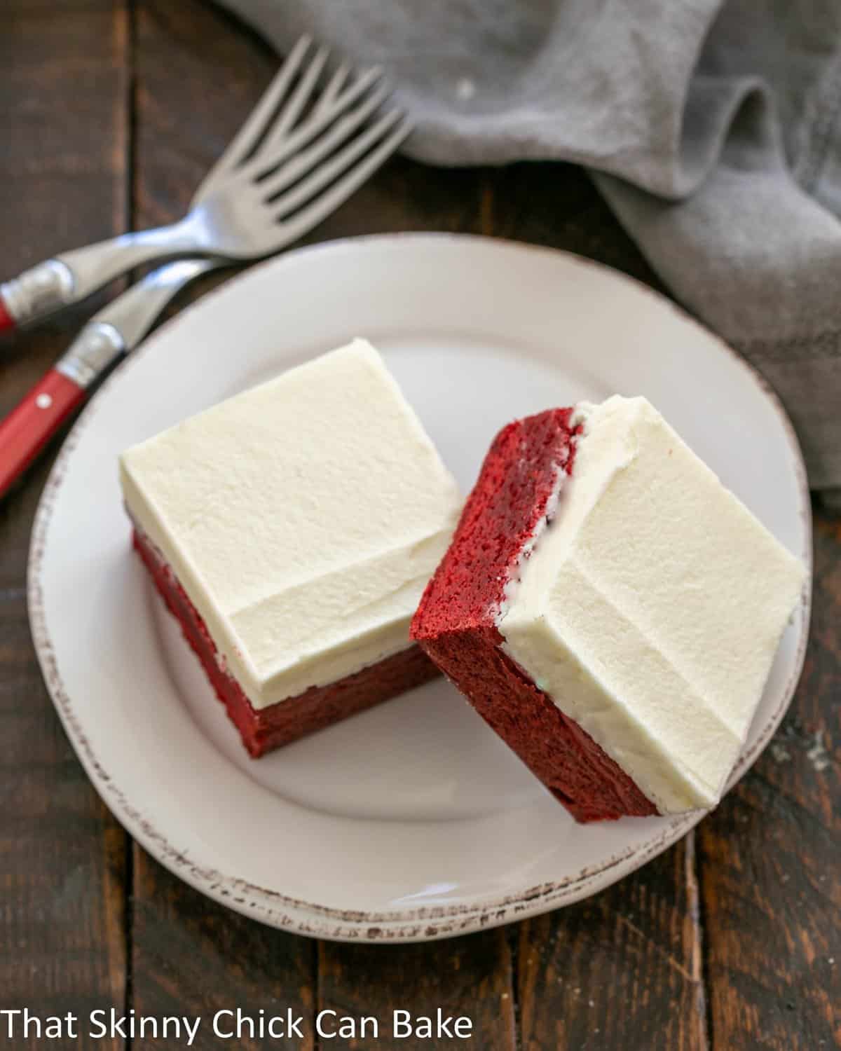 Overhead view of 2  red velvet brownies on a white dessert plate.