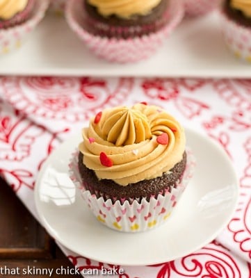 A chocolate cupcake with a swirl of caramelized white chocolate ganache on a small white plate.