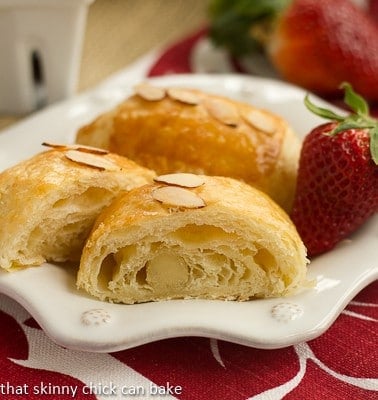 Homemade Almond Croissants on a white decorative plate with a strawberry.