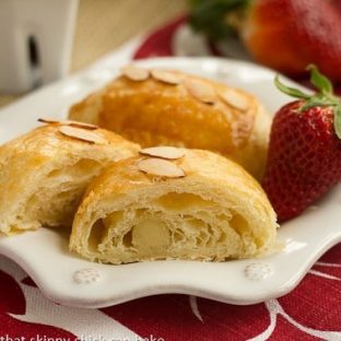Almond croissants on a white plate with a fresh strawberry