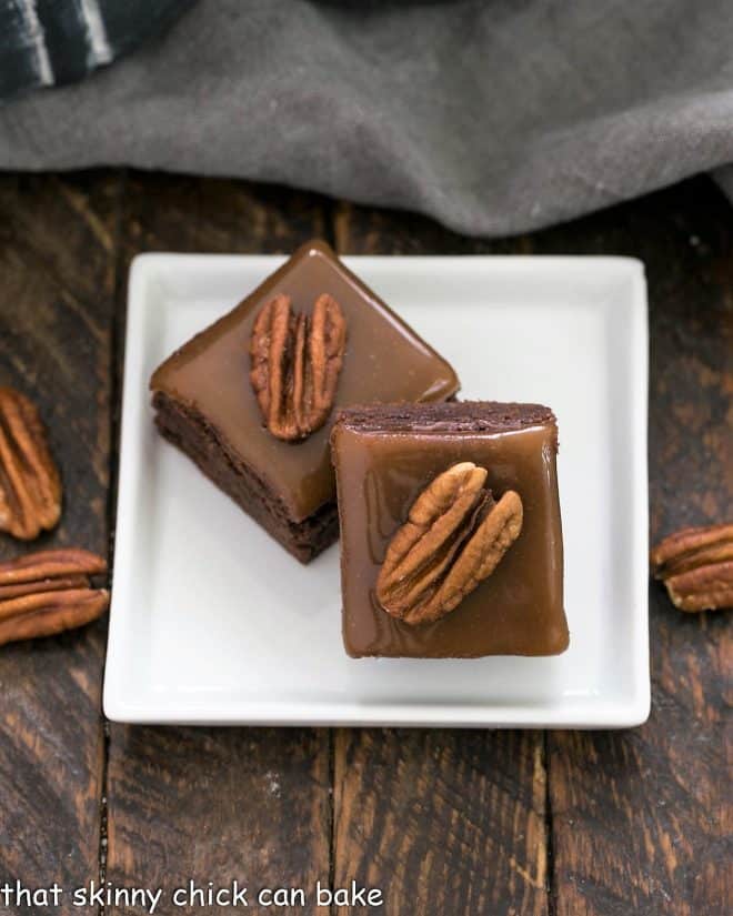 2 turtle brownies on a square white plate.