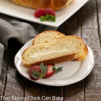 2 slices of cream cheese filled easter bread on a round white plate with strawberry garnish