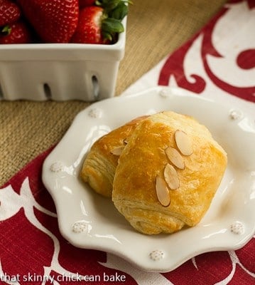 Two almond topped Homemade Almond Croissants on a white ceramic plate.