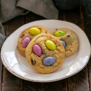 3 easter M&M cookies on a ceramic white dessert plate.