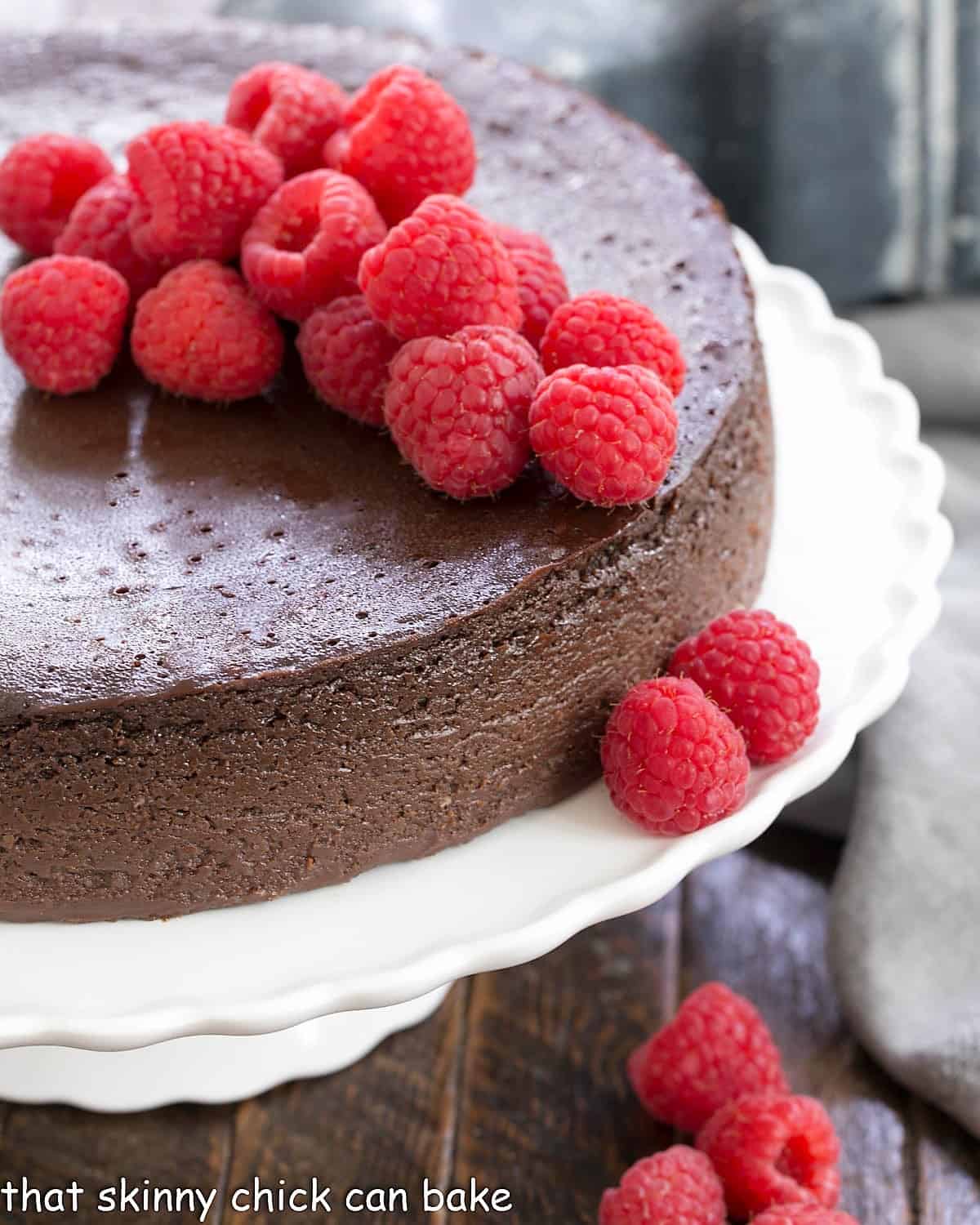 Chocolate Kahlua Cake on a white cake stand topped with fresh raspberries.