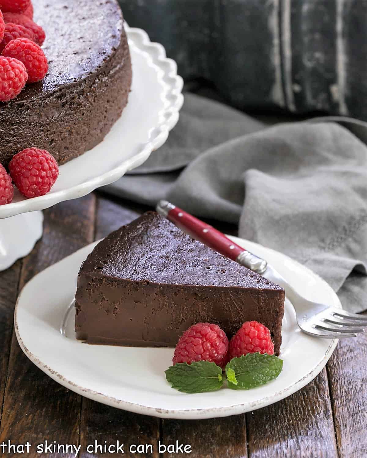 Flourless Chocolate Kahlua Cake slice next to the cake on a cake stand.