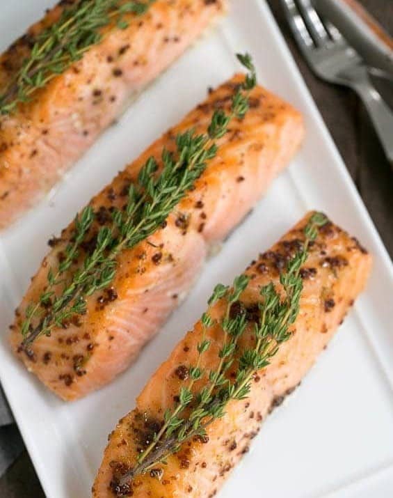 Salmon on serving tray topped with sprigs of thyme.
