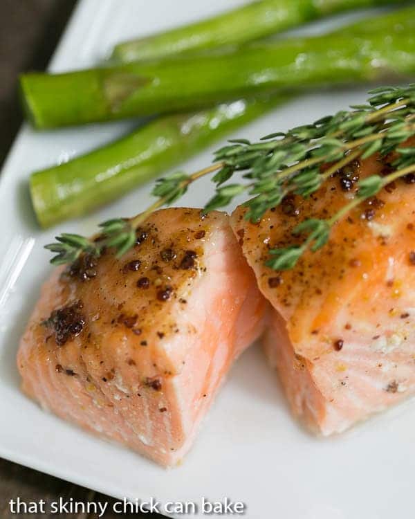 Maple Mustard Glazed Salmon with the center exposed on a white plate topped with fresh thyme.