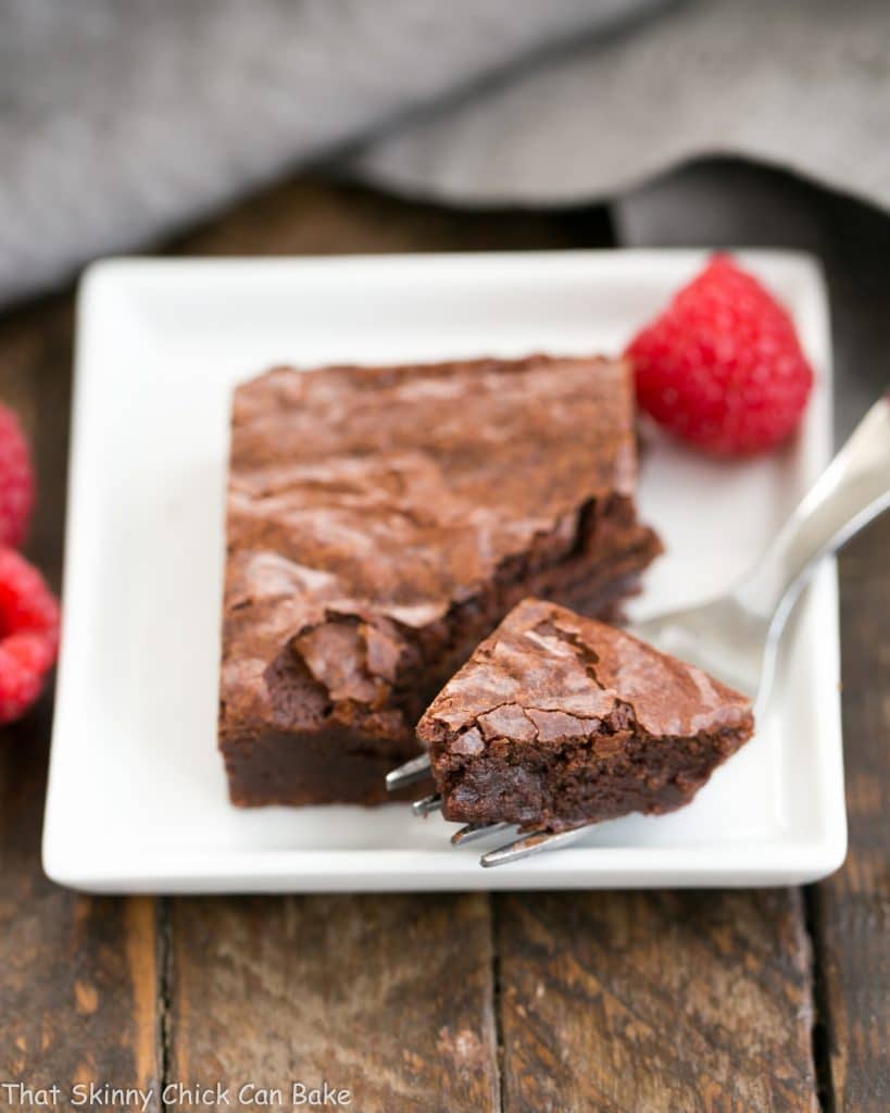 Best Fudgy Brownies on a square plate with a fork removing a bite.
