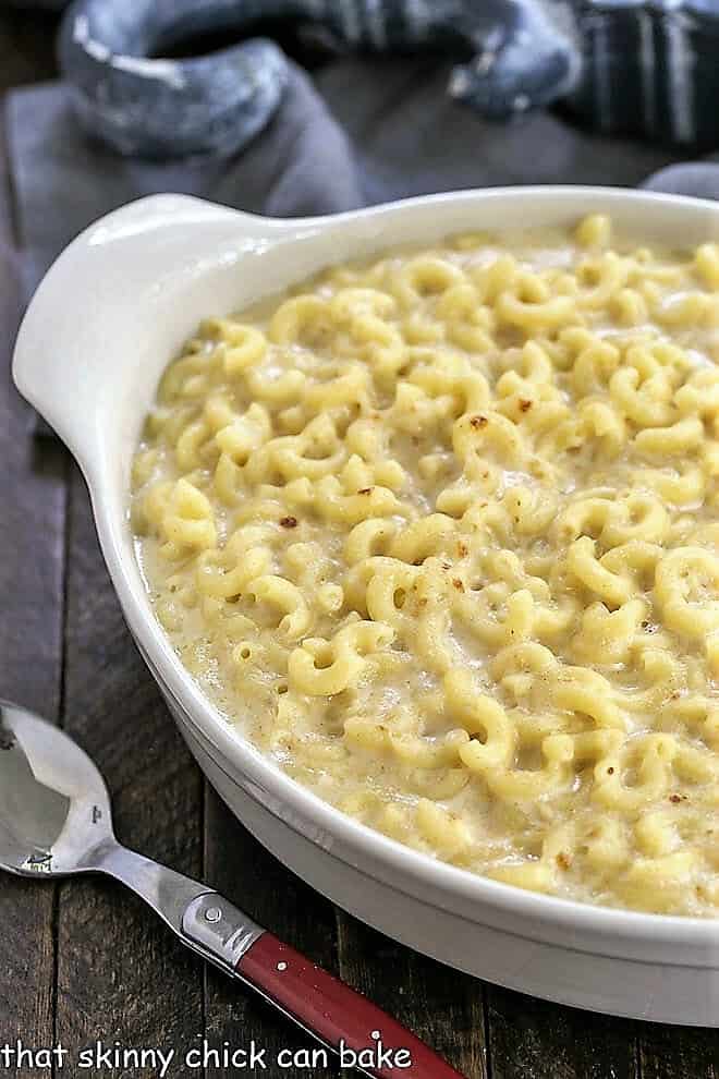 Classic Macaroni and Cheese in a white casserole dish with a red handled spoon