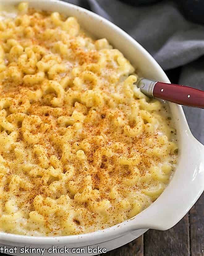 Classic Macaroni and Cheese in a white baking dish with a red handled serving spoon.