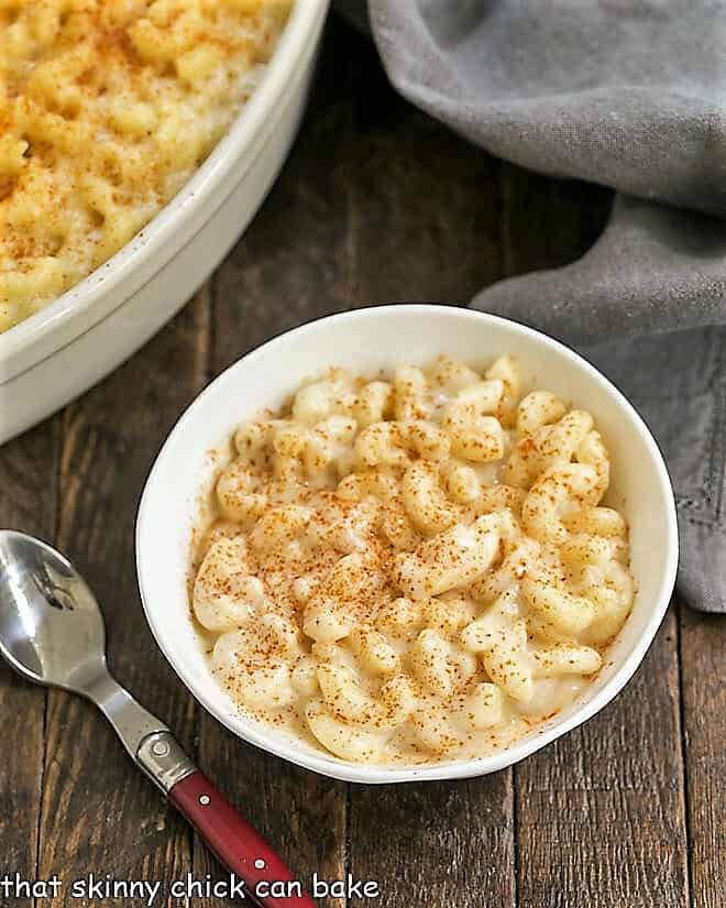 Classic Mac & Cheese in a white dish with a red handled spoon.