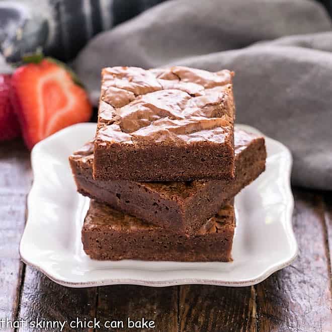 3 fudgy homemade Brownies stacked on a square white plate