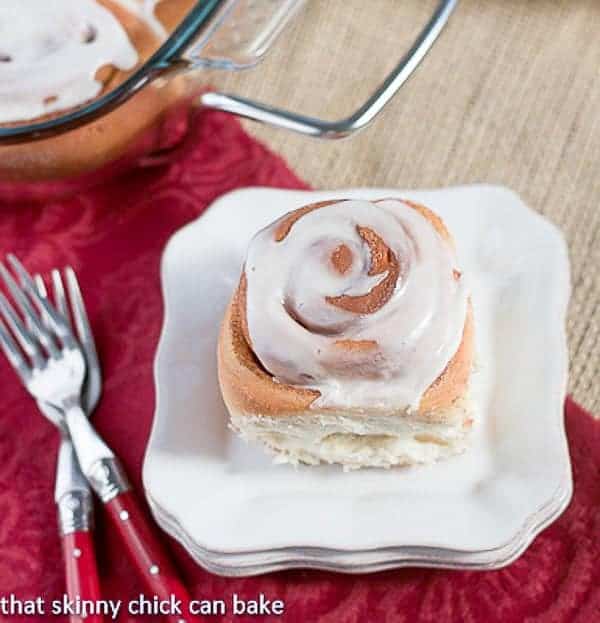 Moomie's Cinnamon Buns - Tender, old-fashioned frosted cinnamon roll on a stack of white plates!