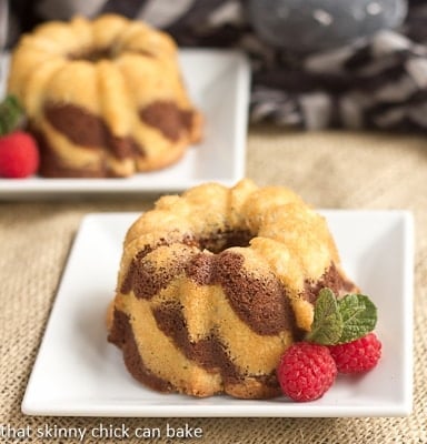 Two mini bundt cakes on square white plates.