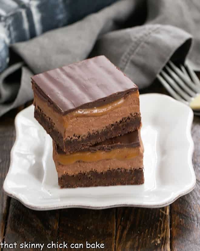 Milky Way Brownies - inspired by the classic chocolate and caramel candy bar! A stack of 2 Milky Way Brownies on a white plate.