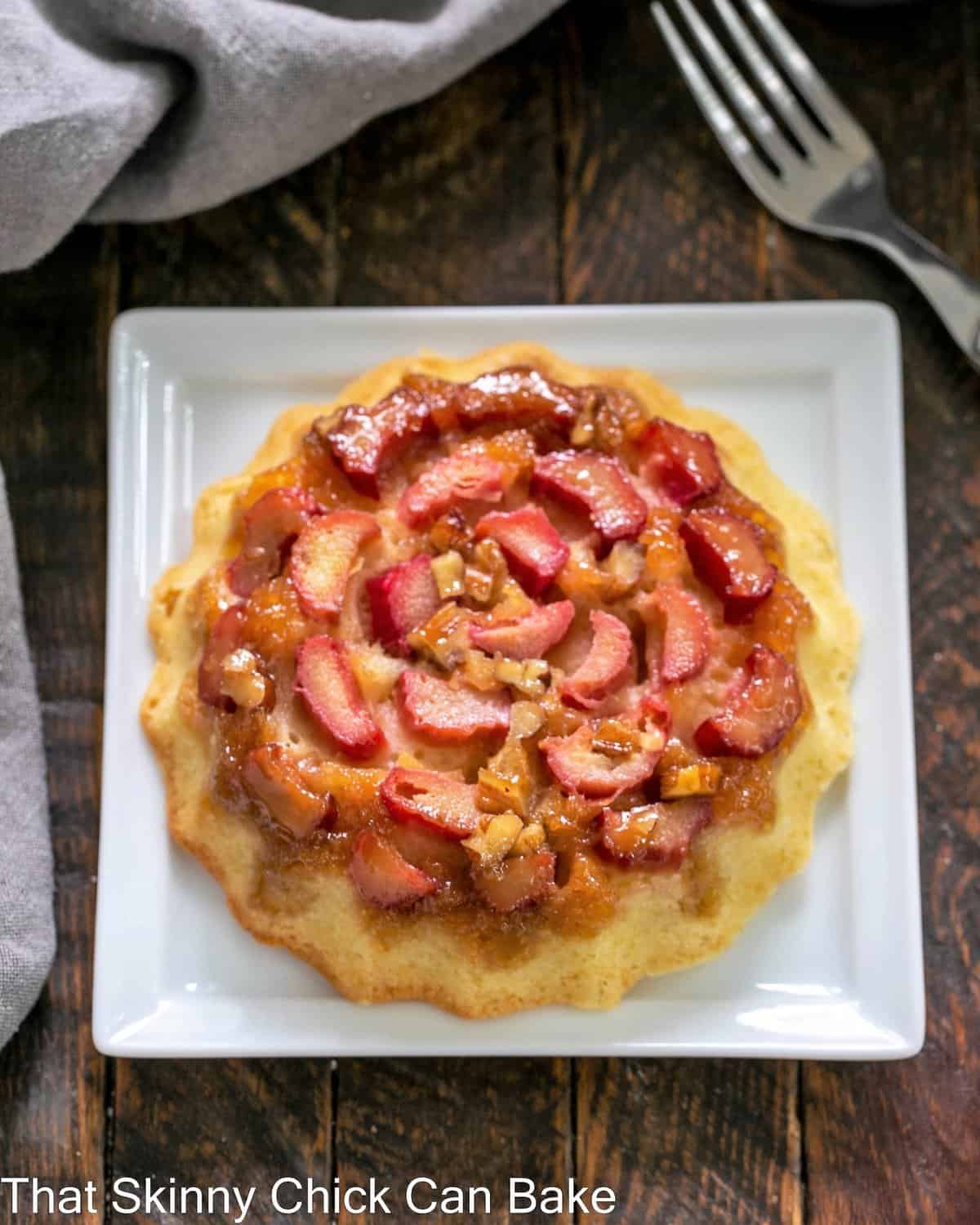 A single rhubarb baby cake on a square white plate.