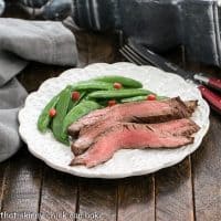 Korean grilled flank steak and sugar snap peas on a white dinner plate