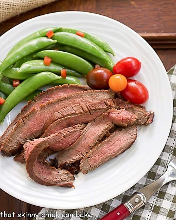 Korean Beef Recipe sliced and plated with sugar snap peas and tomatoes.