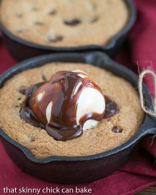 Close up of a Skillet Chocolate Chip Cookie topped with ice cream and chocolate sauce