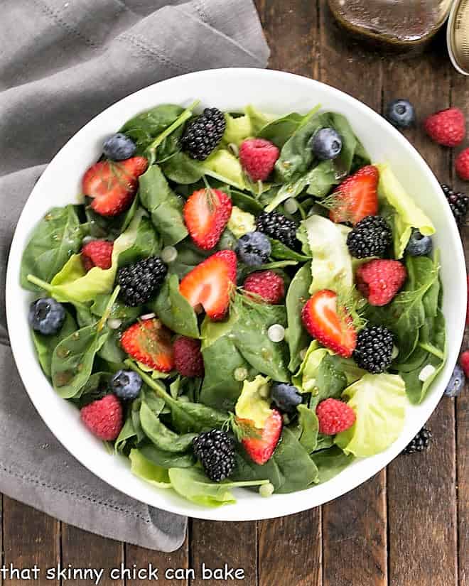 Overhead view of Spinach Almond and Berries Salad in a white bowl.