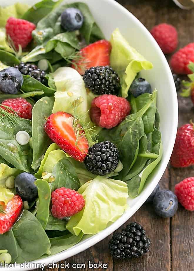 Close view of spinach salad ingredients in a white bowl.