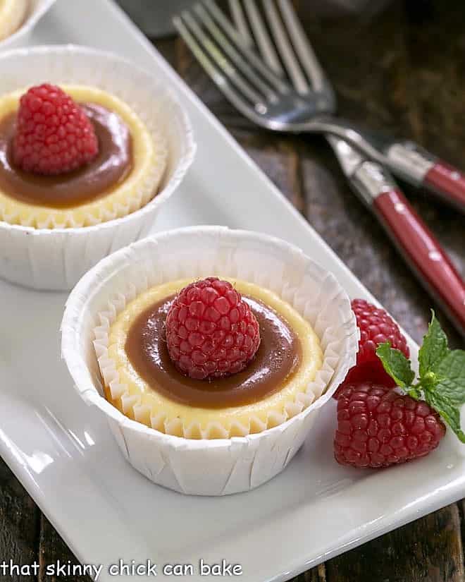 2 Caramel Topped Mini Cheesecakes on a white tray.