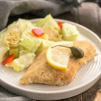 Easy Skillet Chicken Piccata on a round white plate with a lettuce salad