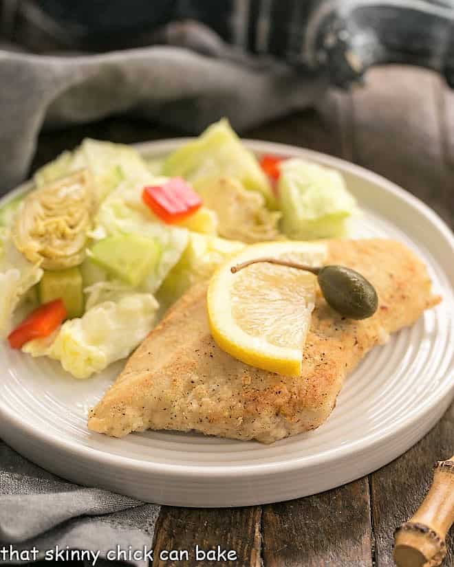 Easy Skillet Chicken Piccata on a round white plate with a lettuce salad