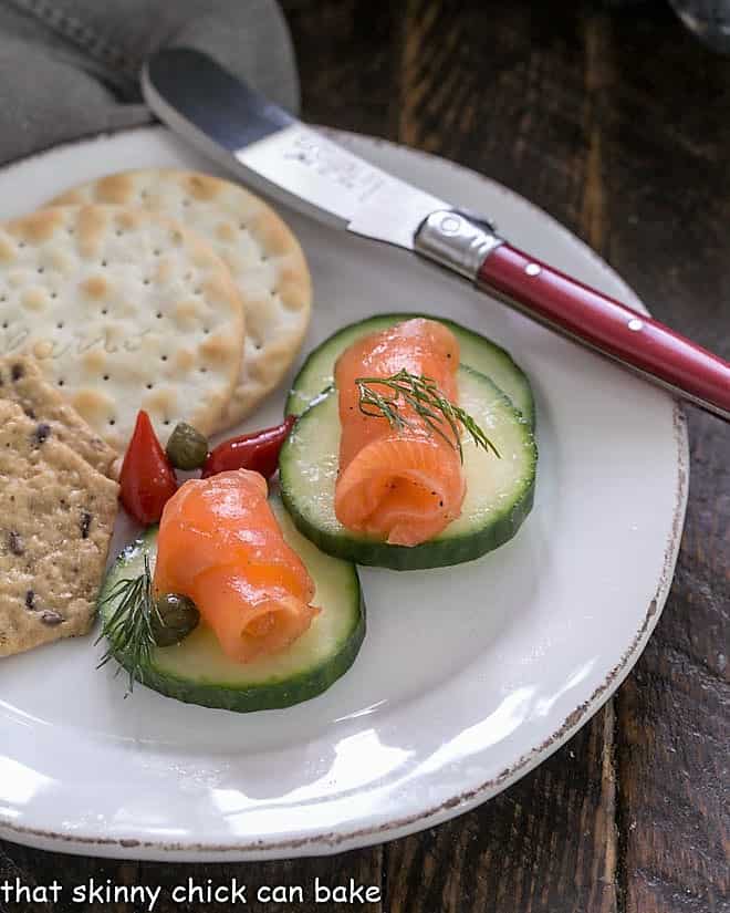 Gravlax on cucumber slices on a white appetizer plate.