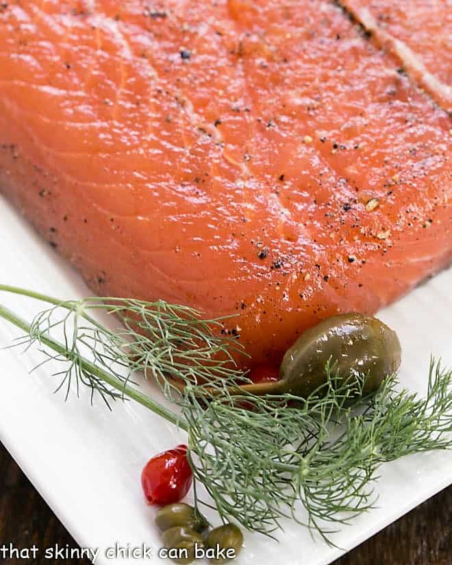Close up of gravlax on a white platter with dill garnish.
