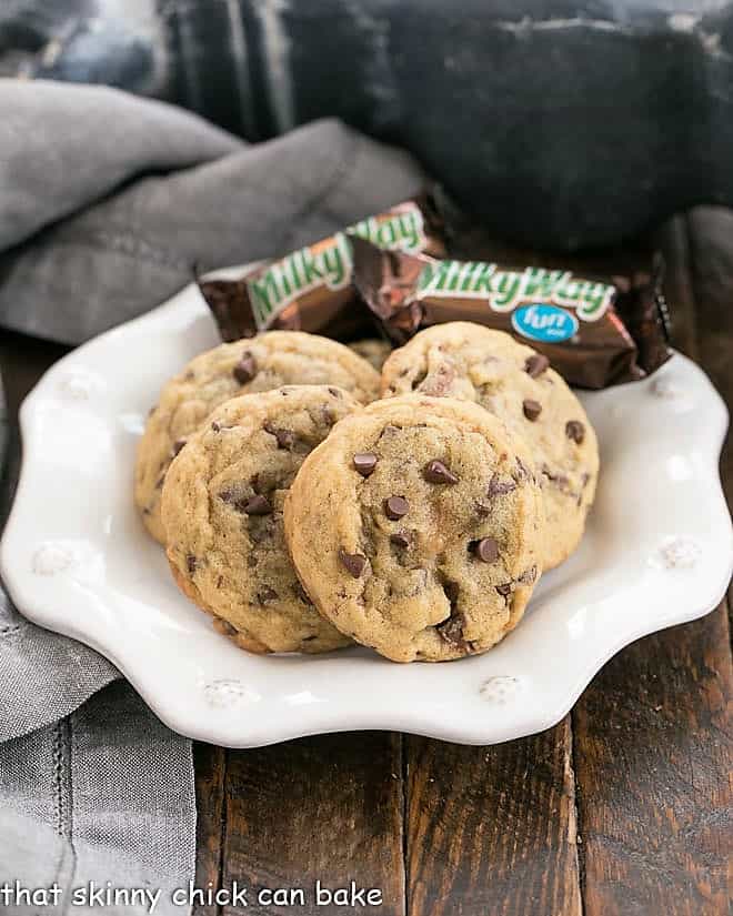 4 Milky Way Chocolate Chip Cookies and 2 small Milky Way bars on a decorative white plate