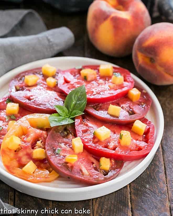 Tomato salad with a peach vinaigrette on a round white plate