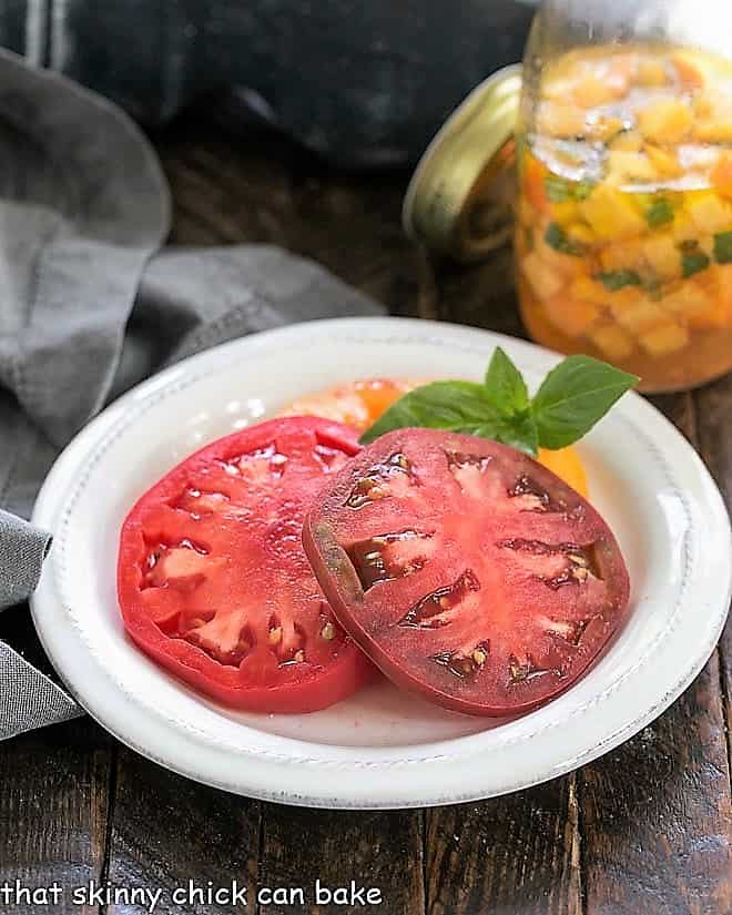 Tomatoes on a small white plate with a peach vinaigrette in the background