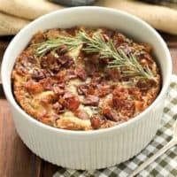 Prosciutto, Gorgonzola and Rosemary Strata in a round casserole dish with a sprig of rosemary to garnish