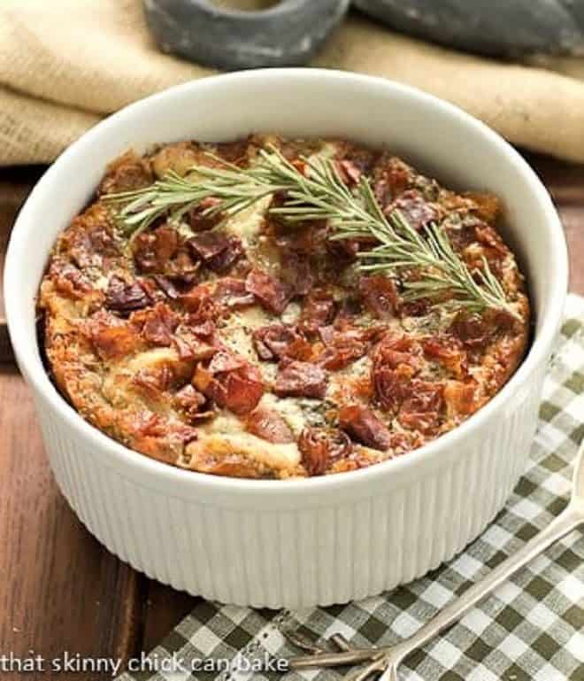 Prosciutto, Gorgonzola and Rosemary Strata in a round casserole dish with a sprig of rosemary to garnish