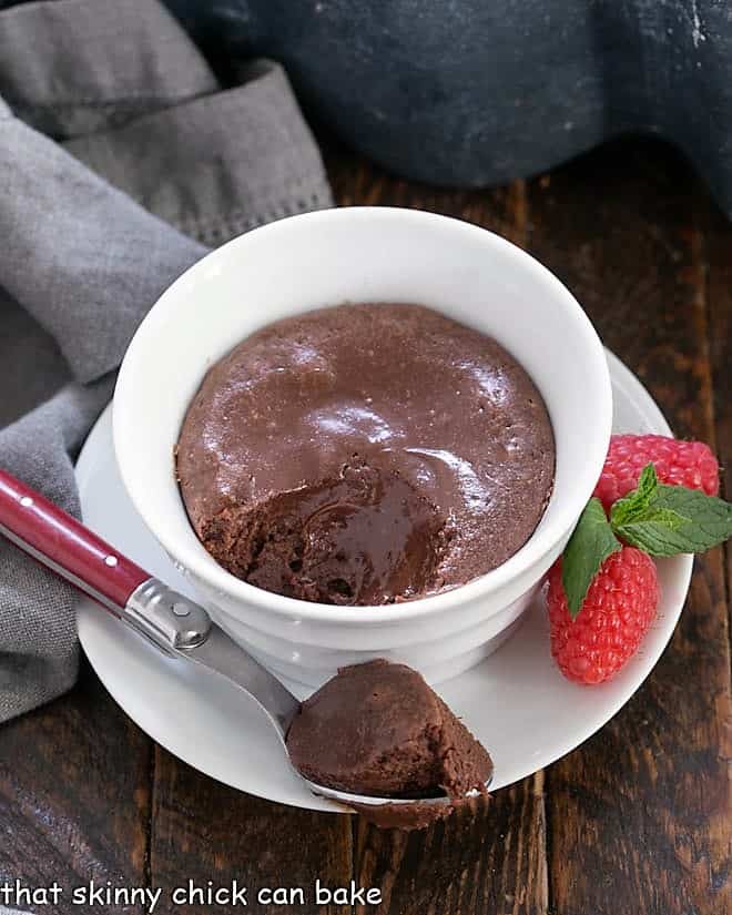 Individual chocolate cheesecakes with a spoonful removed onto a red handled spoon.