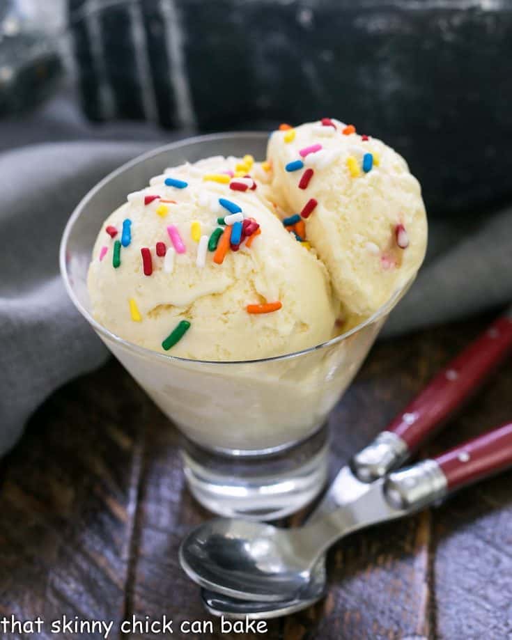 cake batter ice cream in a glass dish with 2 red handled spoons