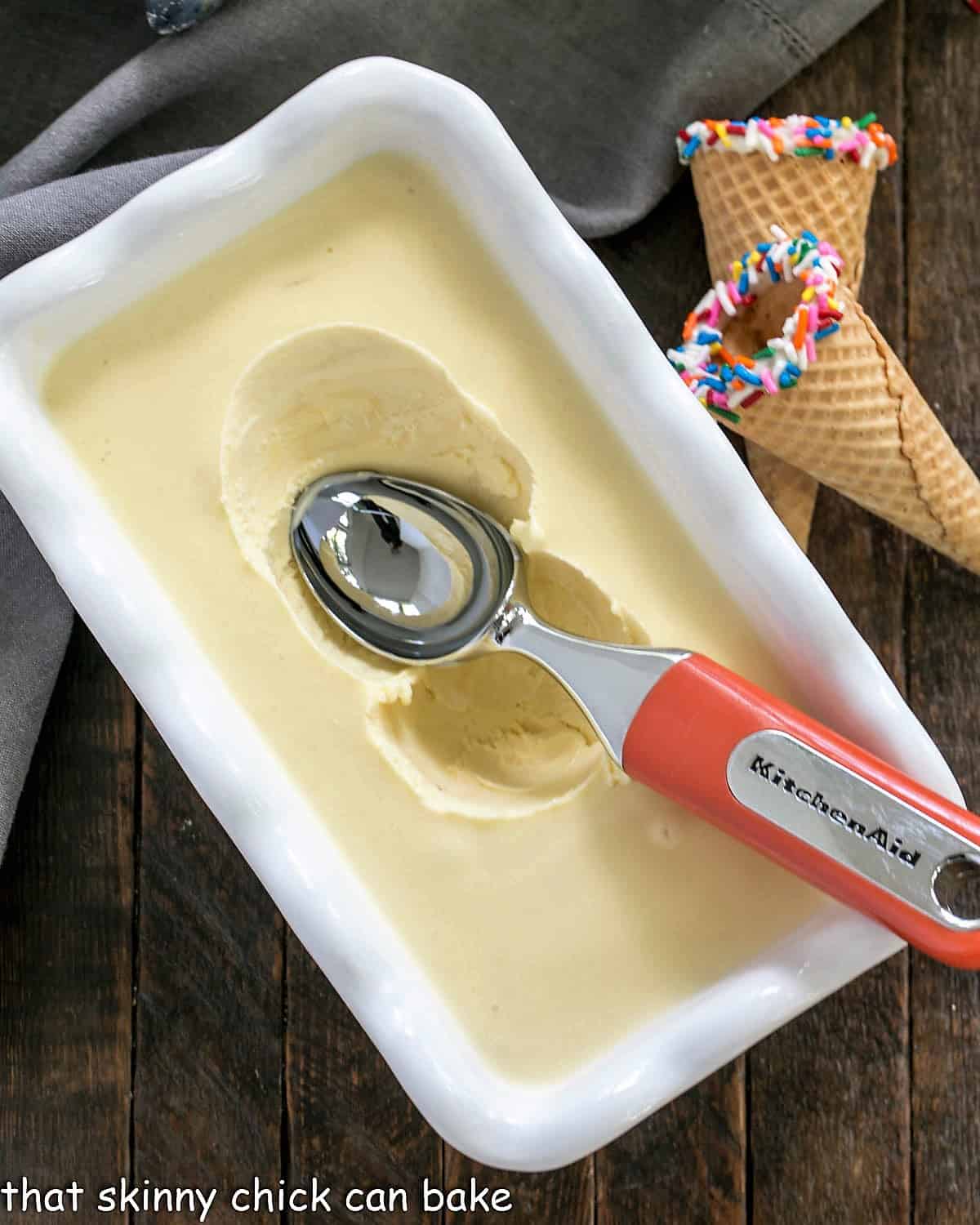 Cake Batter Ice Cream in a freezer dish with an ice cream scooper.