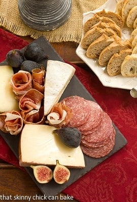 Overhead view of a meat and cheese tray  next to a plate of bread